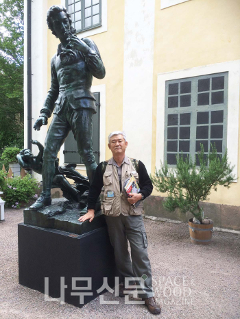 오른손에 들고 있는 꽃을 유심히 관찰하는 린네의 동상과 필자. 린네 박물관 앞 마당.